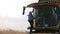 Unrecognizable farmer cleaning his combine after harvesting. Man taking care of technique. Working process on farm. Slow