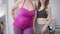 Unrecognizable fat and slim women standing indoors posing. Obese and slender Caucasian young ladies in sportive clothes