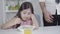 Unrecognizable father gesturing emotionally and making late time gesture as little girl having no appetite mixing