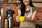 Unrecognizable female barista welcoming guests at coffee house counter, offering cup of hot beverage, closeup, crop