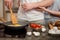 Unrecognizable female and male fry together eggs and make tomatoes salad, stand on kitchen, prepare breakfast involved