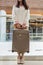 Unrecognizable female passenger holding suitcase posing at duty free international airport terminal