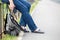 Unrecognizable female sitting on steel fence of pedestrian pathway with mobile phone in hands, urban backpack standing on earth