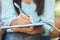 Unrecognizable female student sitting outdoors, making notes, closeup