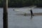 unrecognizable fisherman from the distance shore,throwing fishing net to catch fish.