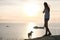 Unrecognizable girl with dog admires the sunset on a mountain with seascape. Side view
