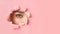 Unrecognizable Girl Looking At Camera Through Hole In Pink Paper