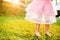 Unrecognizable girl in princess skirt running in sunny garden