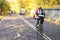 Unrecognizable guy, back to us riding bike in autumn park, bright colorful trees, sunny day, fall foliage. Healthy