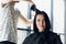 Unrecognizable hairdresser creating hairstyle for beautiful brunette woman