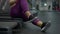 Unrecognizable heavyset Caucasian woman sitting on treadmill resting after training. Overweight plus-size sportswoman