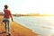 Unrecognizable Hiker Girl In Jeans Walks Along The Seashore With Binoculars, Rear View. Scout Wanderlust Holidays Concept