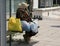 Unrecognizable homeless woman sit on a bus stop. Homeless people. Person in need. Hungry people. Poor person