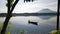 Unrecognizable lake boatman maneuvers his wooden row boat across the lake. Tree obscure the view