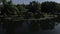 Unrecognizable lake boatman maneuvers his wooden row fishing boat on the lake shore. Top tracking drone aerial shot