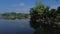 Unrecognizable lake boatman maneuvers his wooden row fishing boat on lake shore. Top tracking drone aerial shot