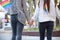 Unrecognizable lesbian couple holding hands wearing LGBT bracelets and with LGBT flags in their pockets.