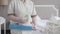 Unrecognizable maid in uniform holding dust brush and liquid cleaner. Chubby Caucasian woman standing in hotel room with