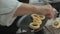 Unrecognizable male chef hands in kitchen restaurant serving cooked deep-fried squid rings, close up