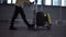 Unrecognizable male passenger with luggage trolley in the international airport. Walking in the hurry, side view