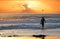 Unrecognizable male surfer walks towards the ocean to ride waves at sunset.