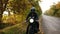 Unrecognizable man in black helmet and leather jacket stopping his vintage motorcycle on the road side on sunny autumn