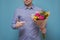 Unrecognizable man in blue shirt holding flowers as gift for his mother or girlfriend on birthday.