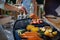 Unrecognizable man grilling ribs and vegetable on grill during family summer garden party, close-up