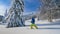 Unrecognizable man hikes in idyllic snowy countryside to splitboard on sunny day