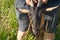 Unrecognizable man holds goat by horns, livestock on pasture