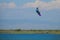 Unrecognizable man jumps in air as he kiteboards along the shoreline of Lefkas.