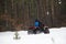 unrecognizable man rides a quad bike off-road in a snowy forest