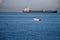 Unrecognizable man sailing on a boat with oars in the sea, a fisherman in a boat over a huge liner