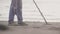 Unrecognizable man scanning sand on the beach with metal detector finding valuables.