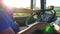 Unrecognizable man sitting behind wheel of his truck and driving through countryside at sunset. Driver holding his hands