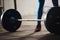 Unrecognizable man standing behind a barbell.