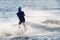 Unrecognizable man trying wakesurfing with multiple splashes and waves