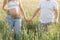 Unrecognizable married couple during their wife& x27;s pregnancy enjoys walk in nature on summer day holding hands