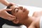 Unrecognizable masseuse massaging relaxed black lady head