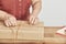 Unrecognizable mature woman wrapping a Christmas gift, using a decorative cord