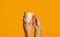 Unrecognizable millennial guy holding cup of aromatic hot drink on orange background, close up