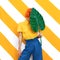 Unrecognizable Model holding palm leaf and wearing vintage look on trendy striped yellow background. Minimal fashion spring summer