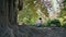 Unrecognizable mother daughter sitting on park bench looking on beautiful tree.