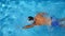 Unrecognizable muscular man swimming in clear blue water of pool. Young sporty guy floating across the basin of hotel on