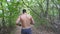 Unrecognizable muscular sportsman running along trail at early autumn forest. Young athlete sprinting along path at