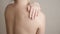 Unrecognizable naked woman smears shoulder with oil