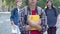 Unrecognizable nerd Caucasian boy standing with books outdoors as classmates laughing at him from the background