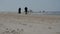 Unrecognizable people silhouettes walking on the beach, slow motion.