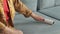 unrecognizable person cleaning grey pillow with lint roller, closeup. Woman cleaning sofa with sticky roller. Dry