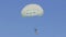 Unrecognizable person flies on white parachute in clear sunny weather